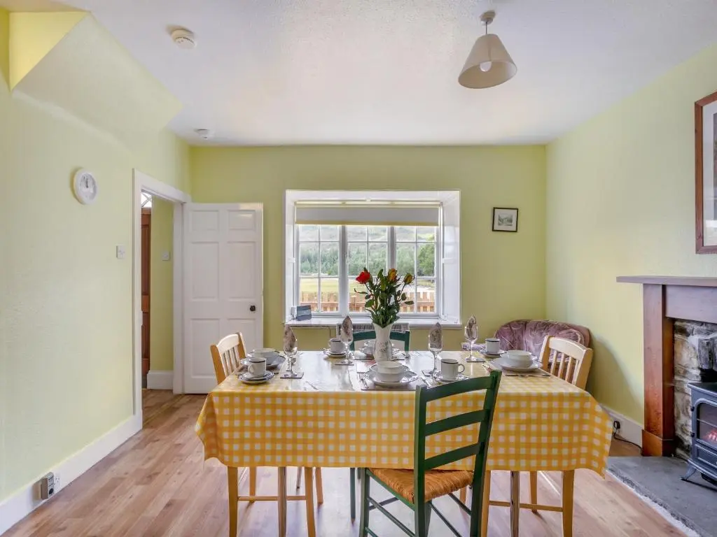 a dining room with a table and chairs and a fireplace at Meall Darroch in Inverey