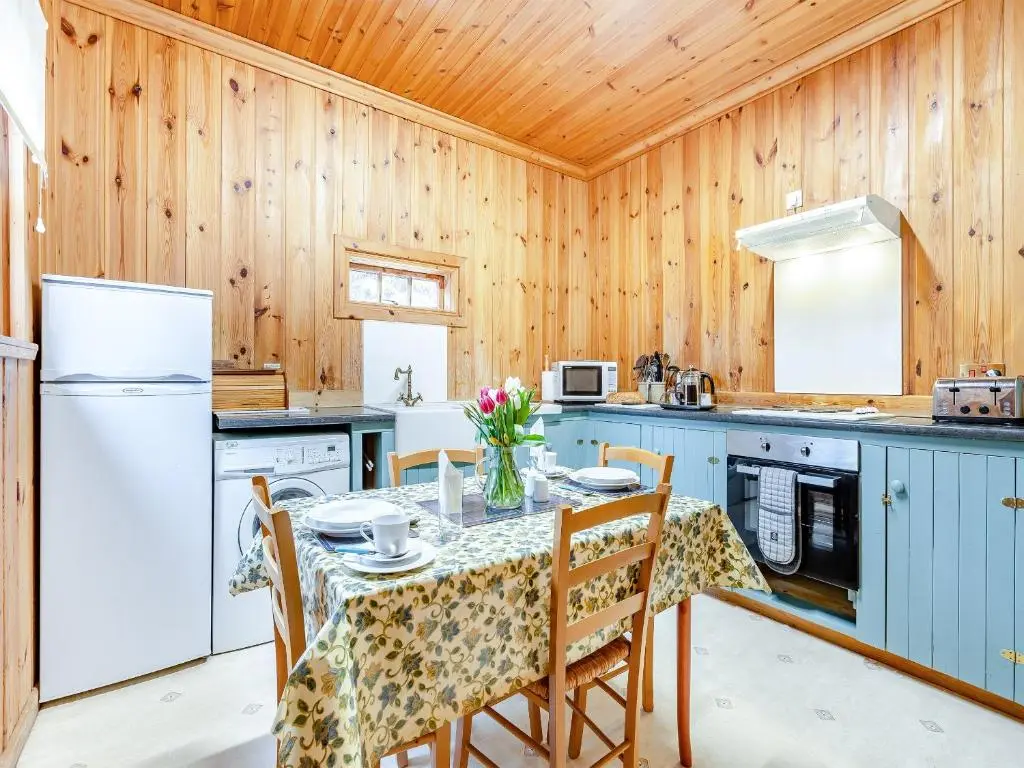 a kitchen with wooden walls and a table with chairs at Stuffer's Cottage in Inverey