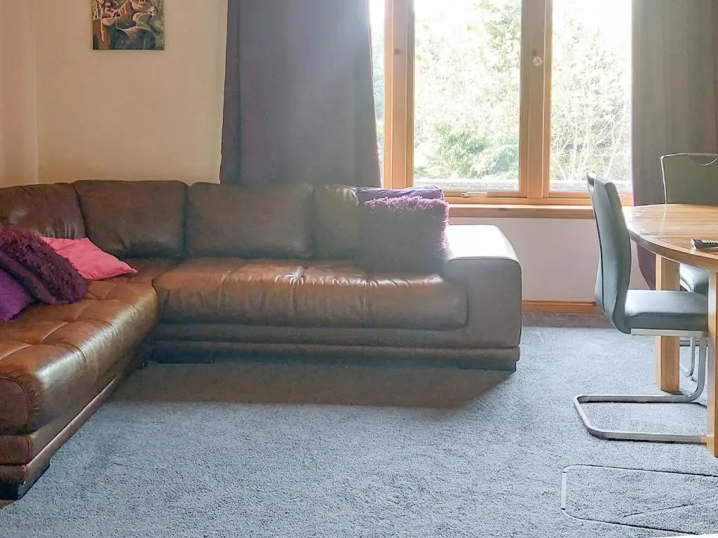 a brown leather couch in a living room with a table at Park Lodge in Strachan