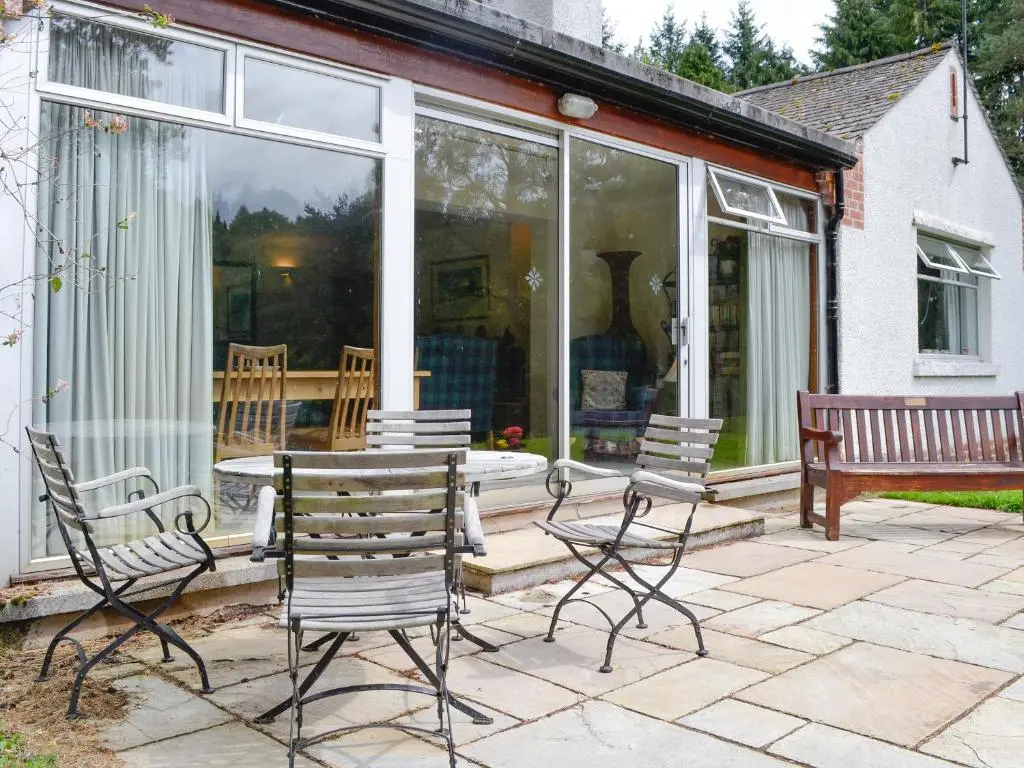 a screened in porch with chairs and a table at Laird's Cast in Banchory