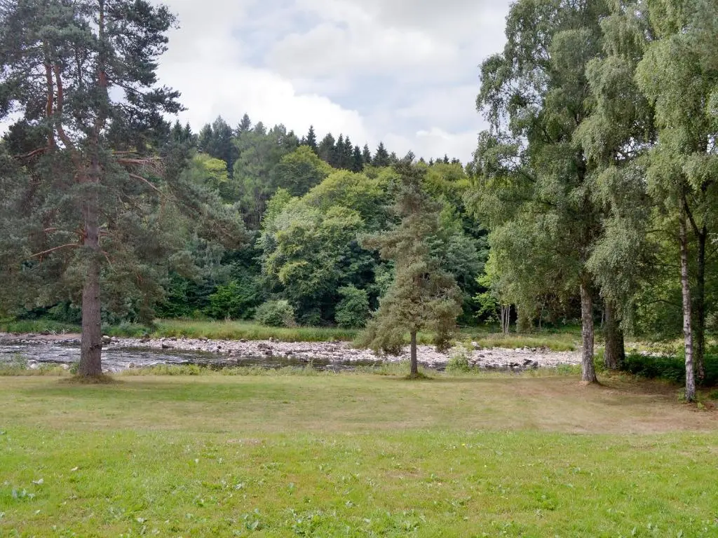 a park with a river and trees and grass at Laird's Cast in Banchory