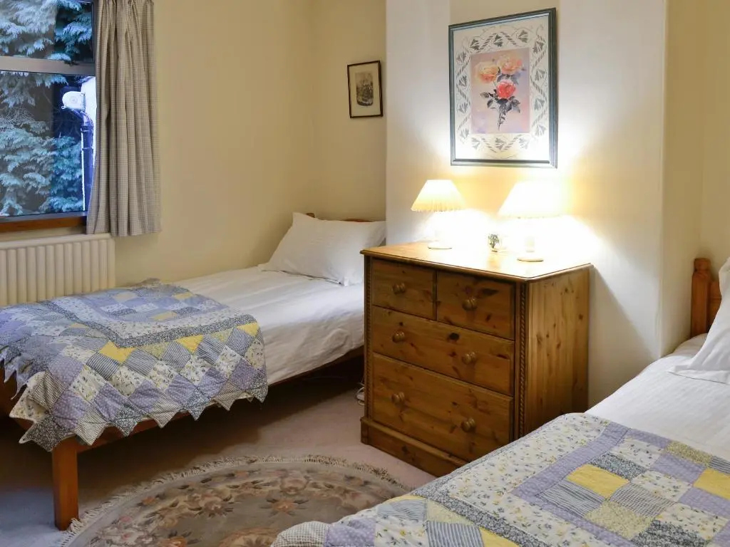 a bedroom with two twin beds and a dresser with a lamp at Laird's Cast in Banchory