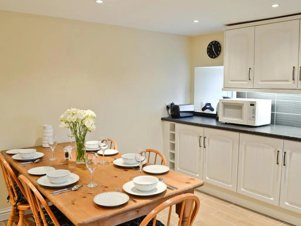 a kitchen with a wooden table with chairs and a microwave at Longcroft Cottage - 28233 in Old Rayne