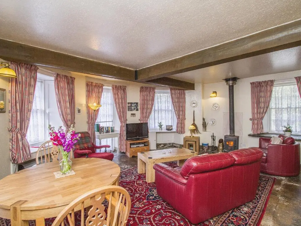 a living room with a red couch and a table at Tinkerbell in Balnaboth