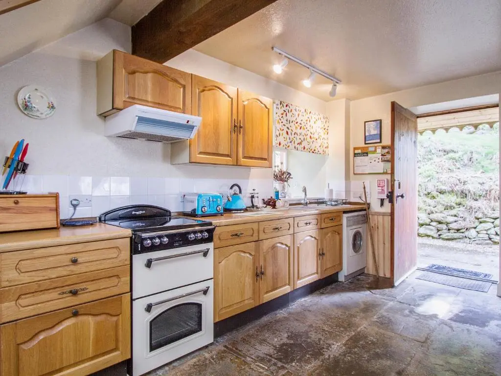 a kitchen with wooden cabinets and a white stove top oven at Tinkerbell in Balnaboth