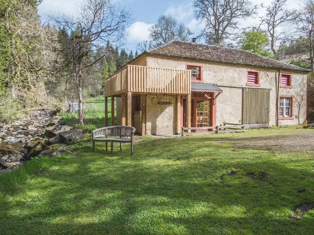 a building with a bench in front of a yard at The Old Laundry in Balnaboth