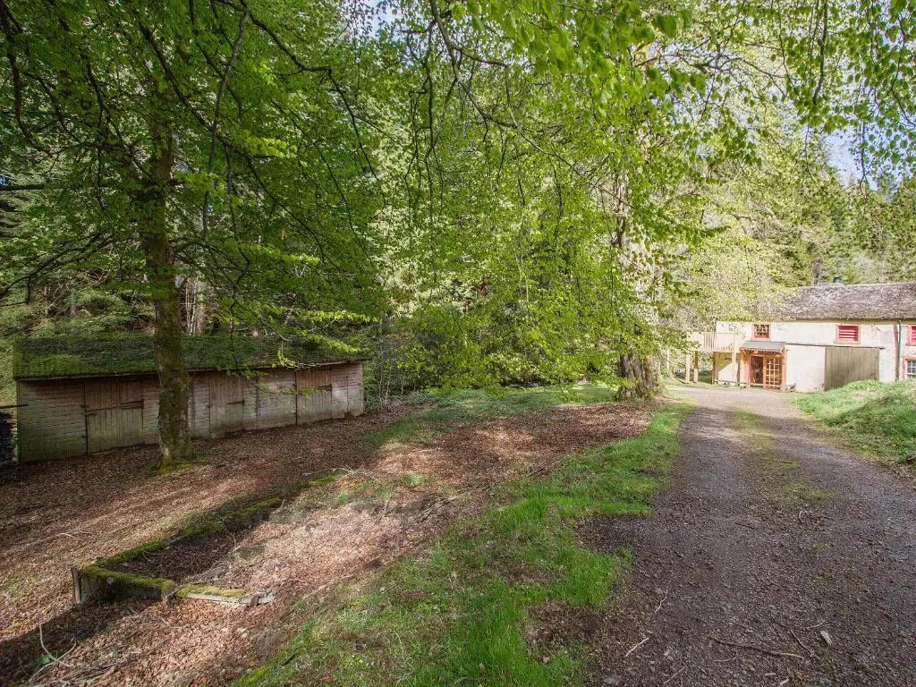 a dirt road in front of a house with trees at The Old Laundry in Balnaboth