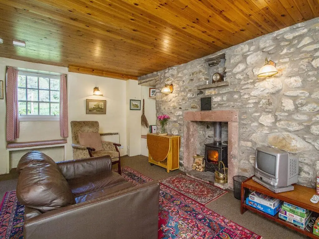 a living room with a couch and a stone wall at The Old Laundry in Balnaboth