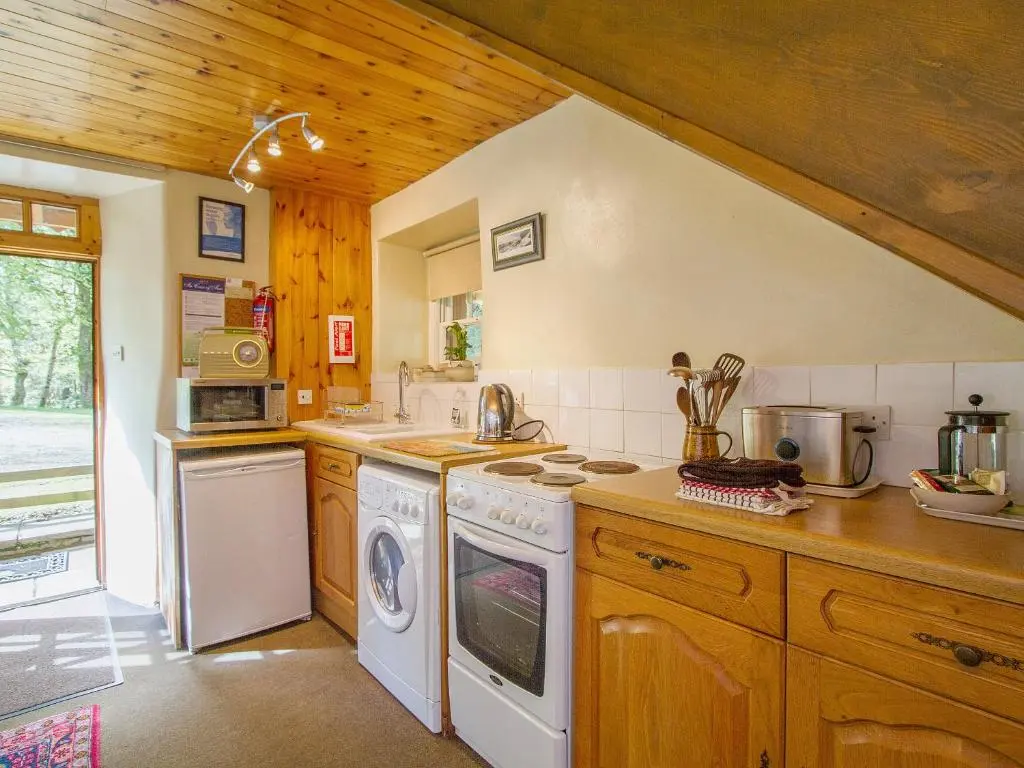 a kitchen with a stove and a washer and dryer at The Old Laundry in Balnaboth