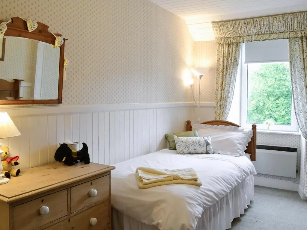 a bedroom with a bed with a dresser and a window at Sunnyside in Kirkmichael