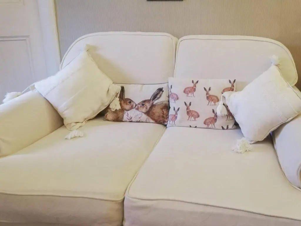 a white couch with pillows and a cat on it at Sunnyside in Kirkmichael