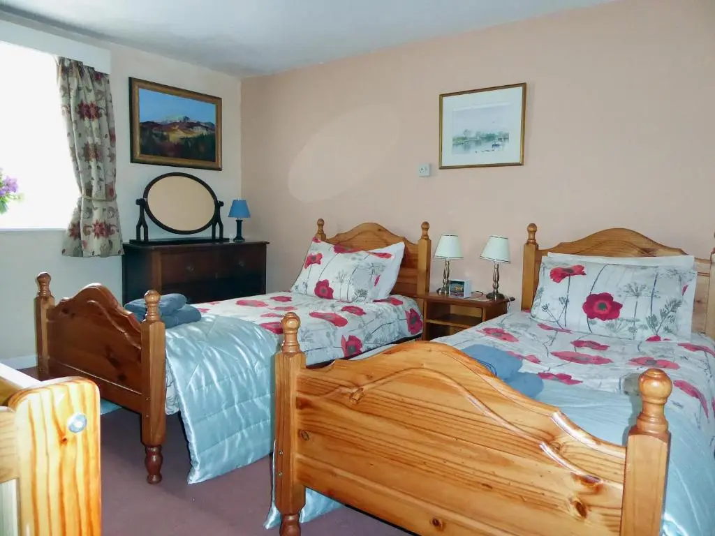 a bedroom with two beds and a mirror at The White House in Pitlochry