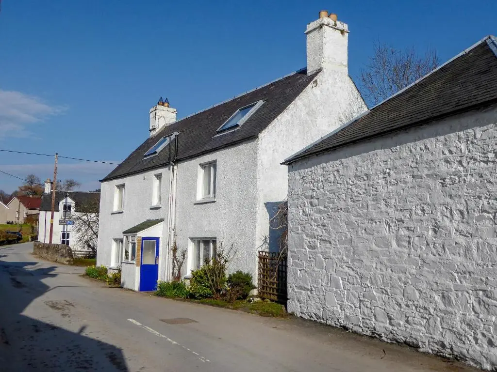 a white house with a blue door on a street at The White House in Pitlochry
