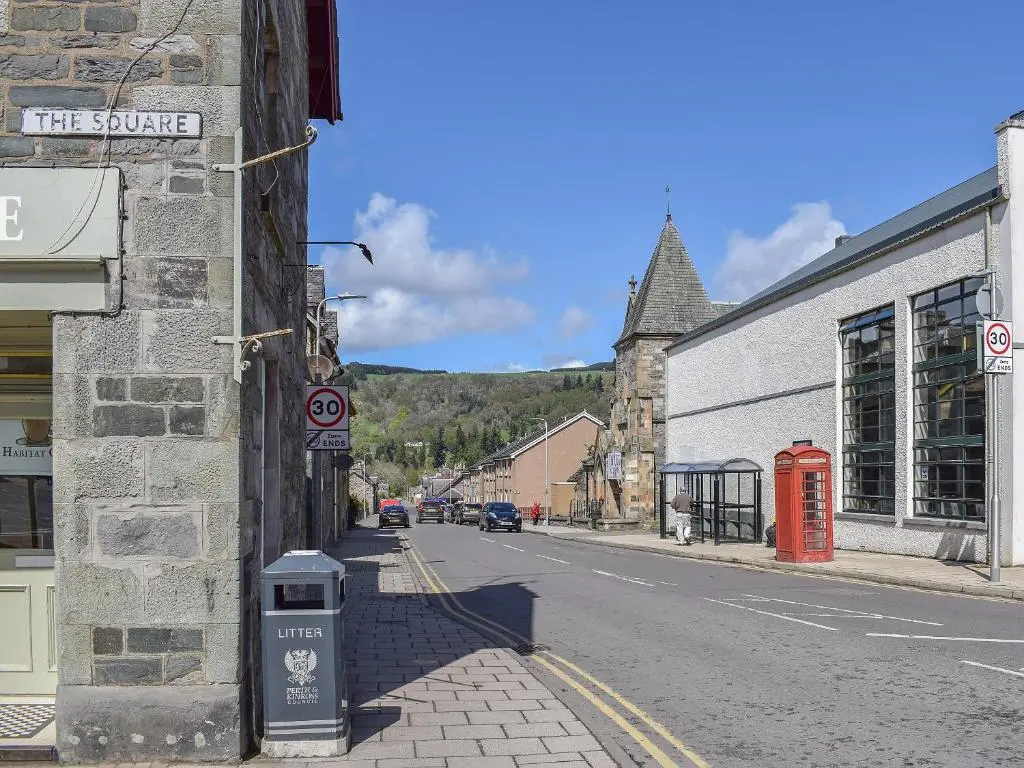 an empty street in a small town with a building at The White House in Pitlochry