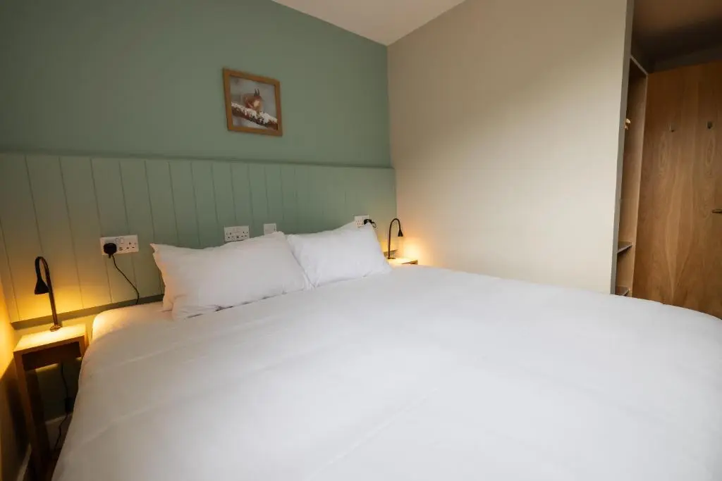 a bedroom with a large white bed with two lamps at An Spiris Accommodation at Dundreggan Rewilding Centre in Dundreggan