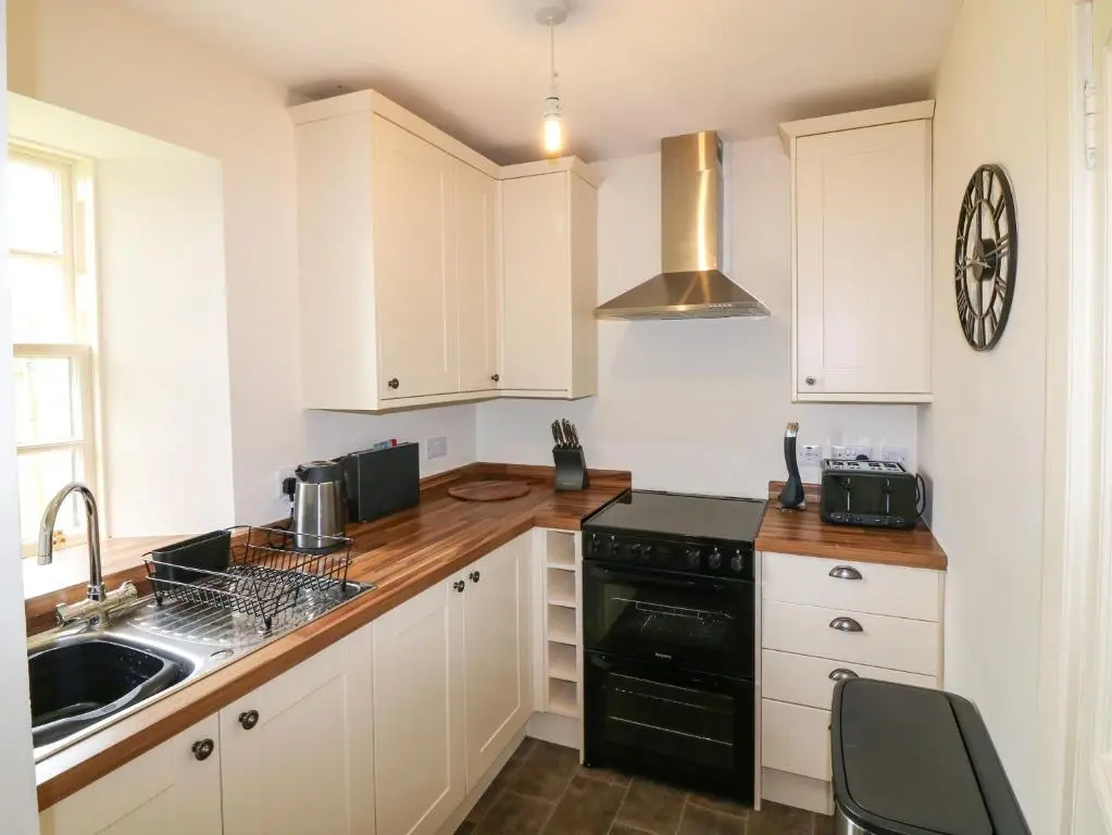 a kitchen with white cabinets and a black dishwasher at Holly Leaf Cottage - Drum Castle Estate in Banchory