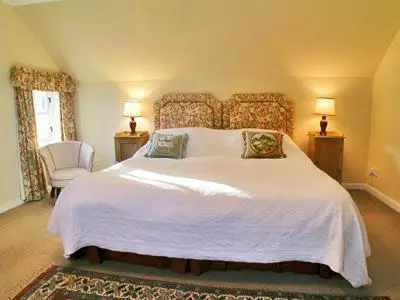 a bedroom with a large white bed and a chair at Dhuallow in Aberarder