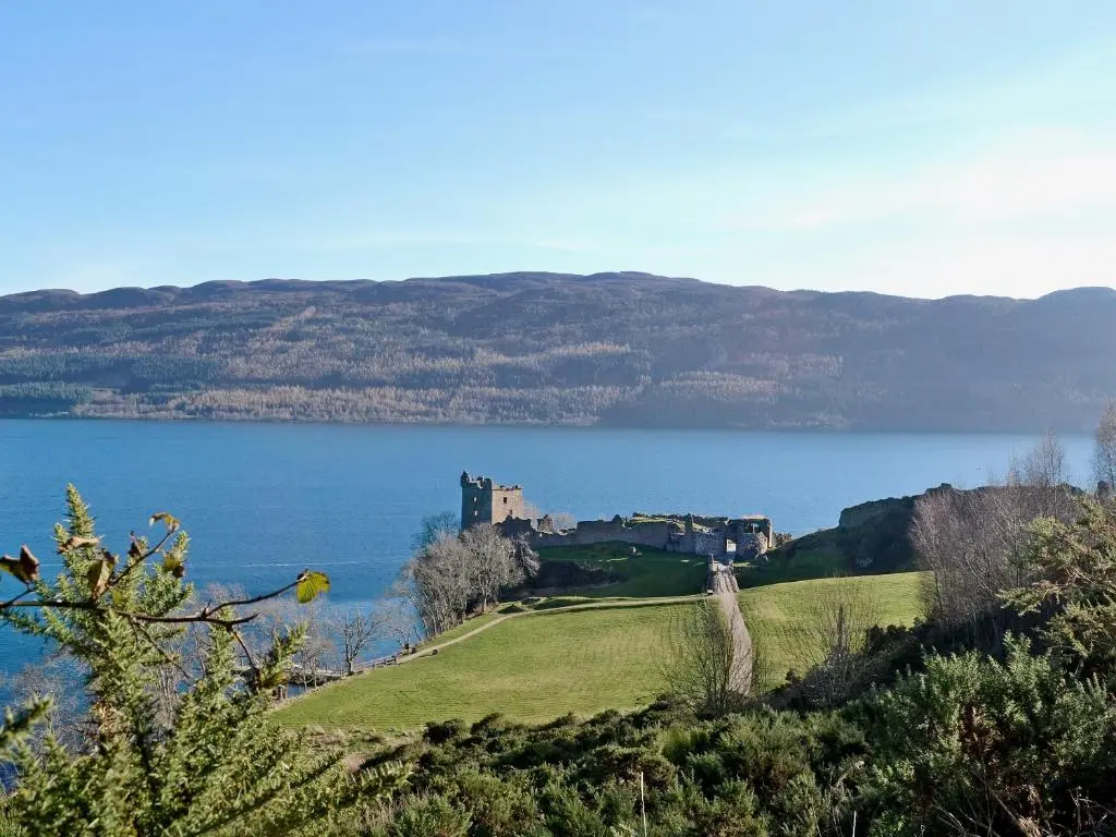 a castle on a hill next to a body of water at Dhuallow in Aberarder