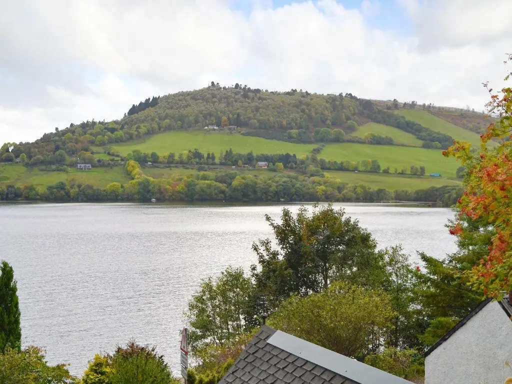 a view of a lake with a hill in the distance at Temple House West in Drumnadrochit