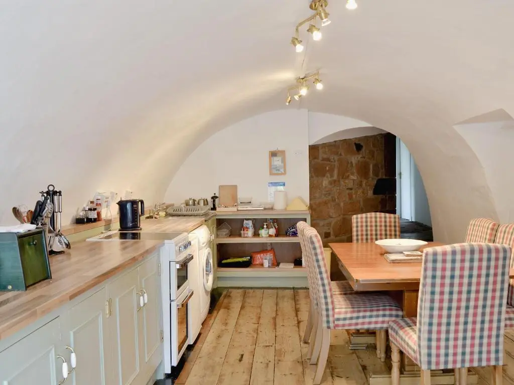 a kitchen with a table and chairs and a kitchen with an archway at Symbister Suite in Turriff