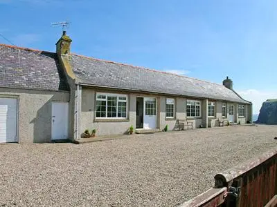 a house with a gravel driveway in front of it at Mill Shore Cottage - 26817 in Pennan