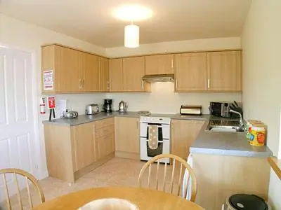a kitchen with wooden cabinets and a table and chairs at Pennan Lodge - 26818 in Pennan