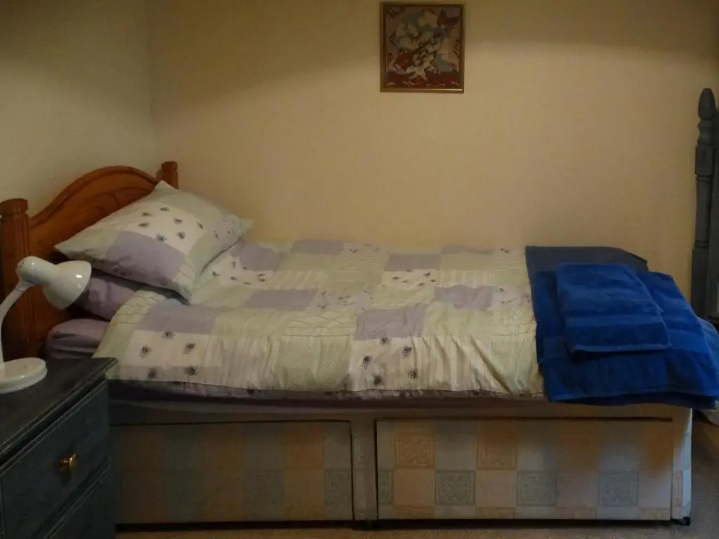 a bedroom with a bed with a blue blanket on it at Scobach Lodge in Turriff