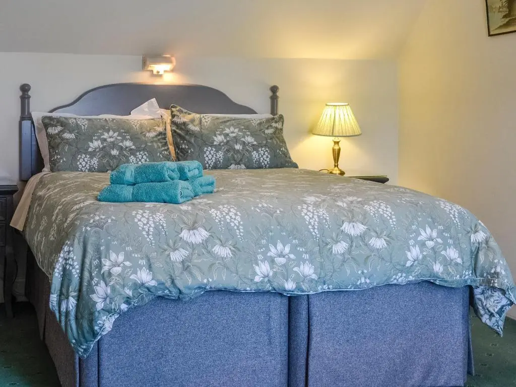 a bed with two blue towels on top of it at St Enodoc in Ullapool