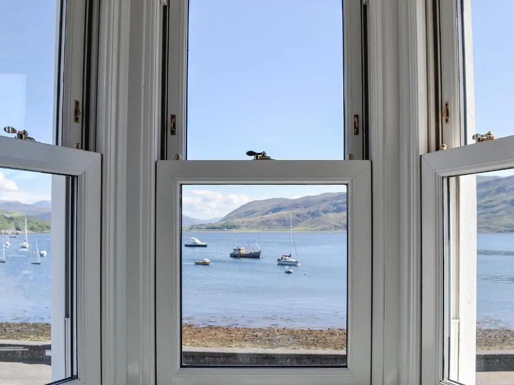 a window in a room with boats in the water at St Enodoc in Ullapool