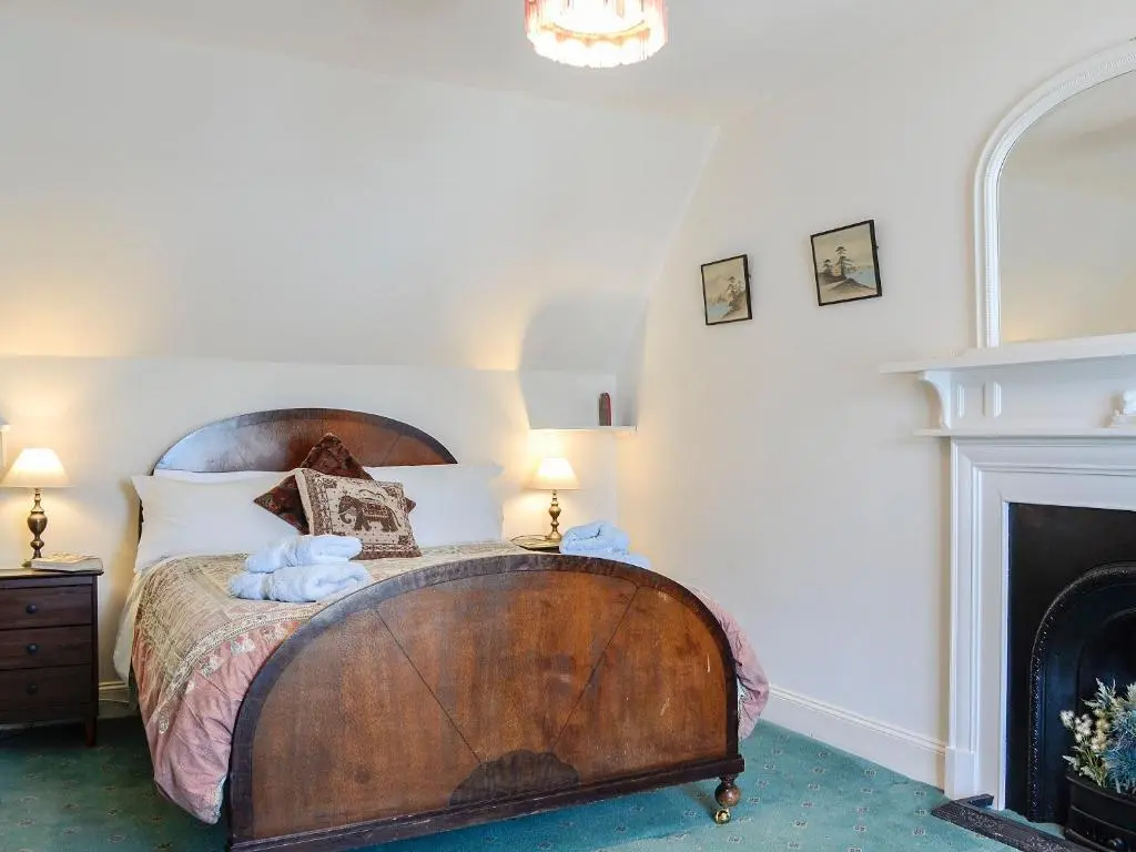 a bedroom with a large wooden bed with a fireplace at St Enodoc in Ullapool