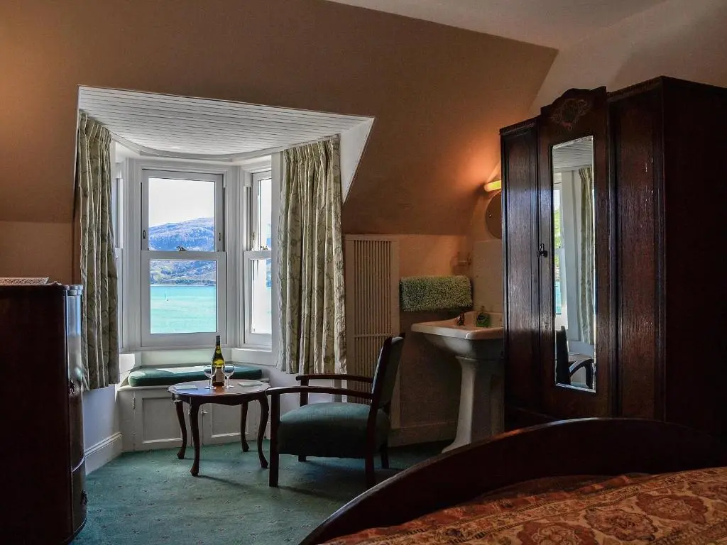 a bedroom with a bed and a table and a window at St Enodoc in Ullapool