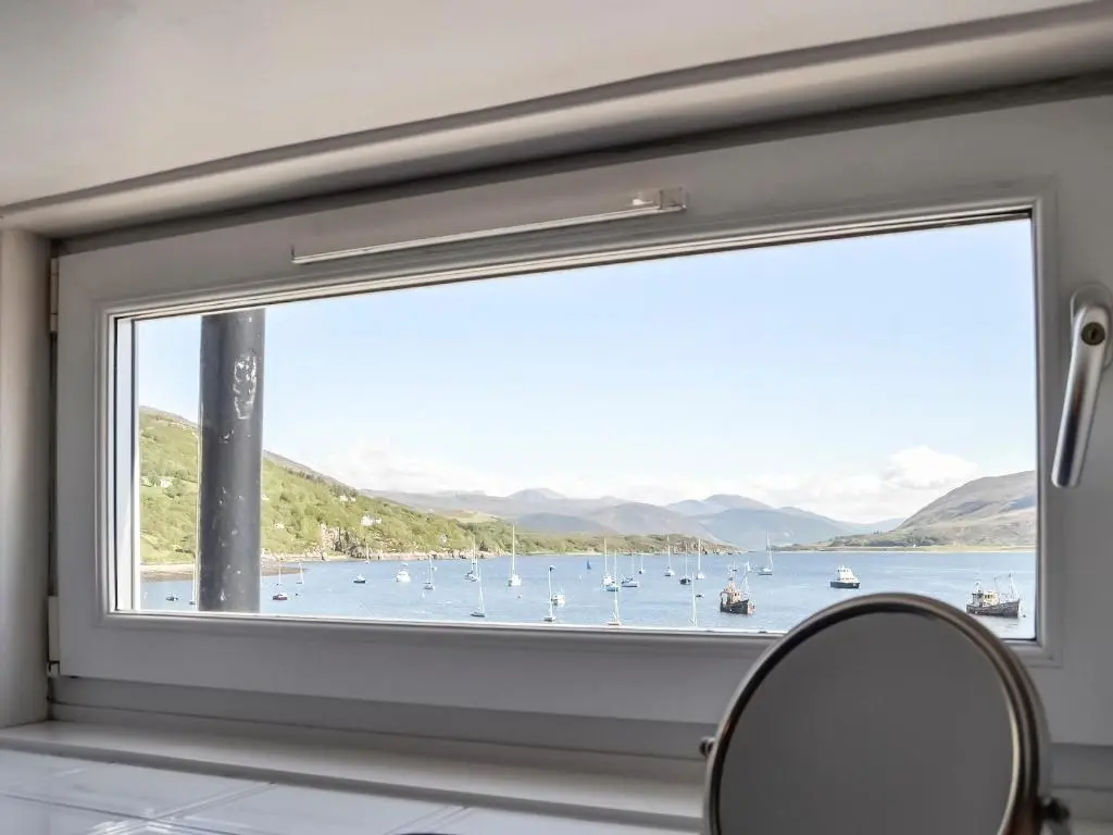 a window in a bathroom with a view of a harbor at St Enodoc in Ullapool