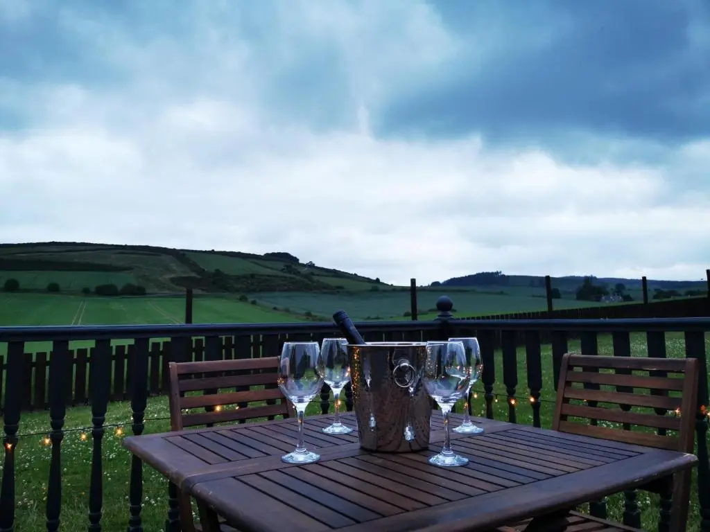 a wooden table with two wine glasses and a bucket at Private peacefull pet friendly converted country cottage in Keig