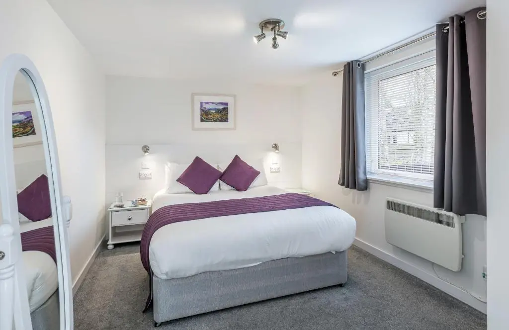 a bedroom with a bed with purple pillows and a mirror at High Range Self-Catering Chalets in Aviemore
