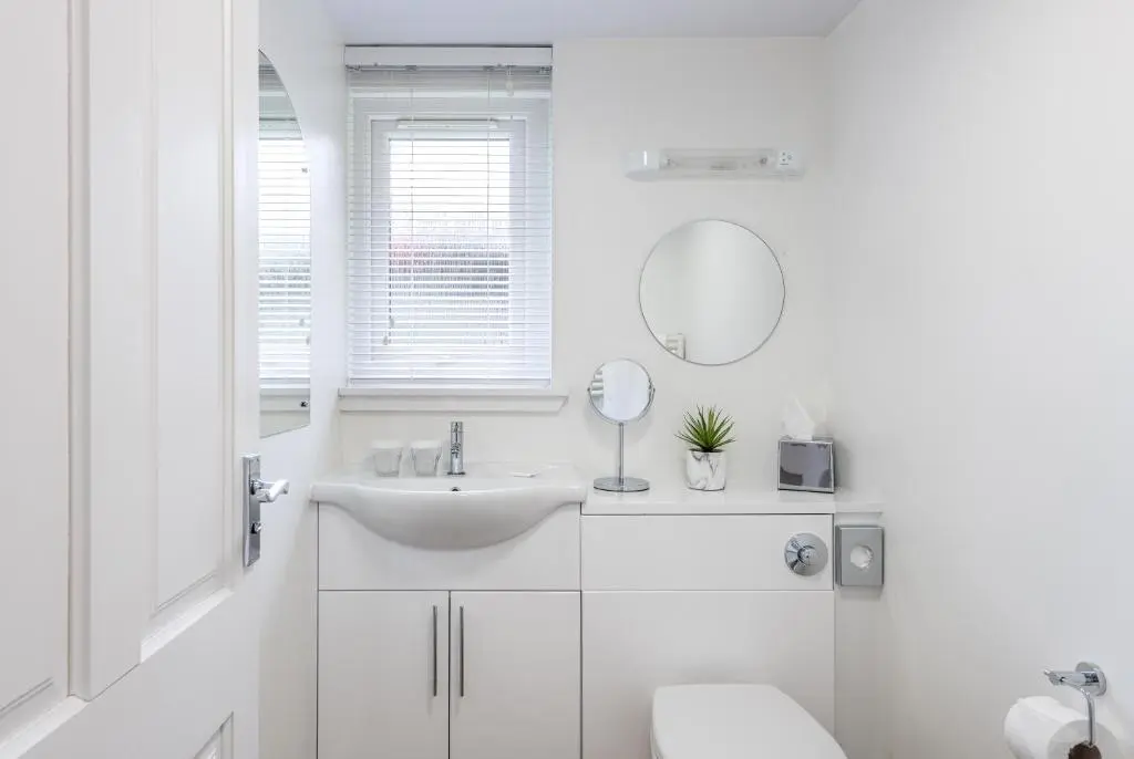 a white bathroom with a sink and a mirror at High Range Self-Catering Chalets in Aviemore