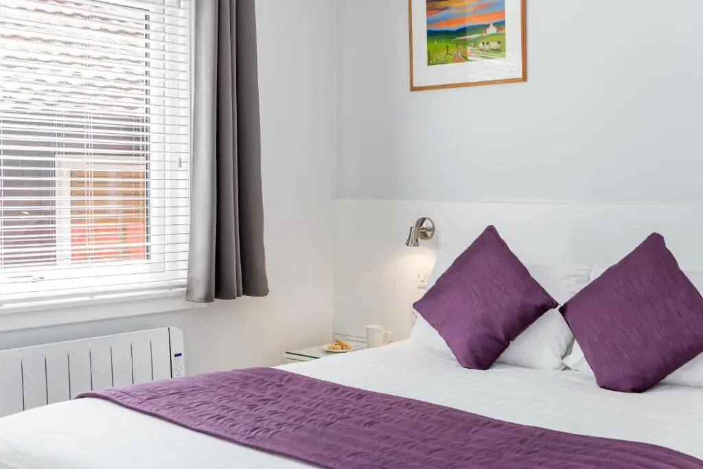 a bedroom with a bed with purple pillows and a window at High Range Self-Catering Chalets in Aviemore