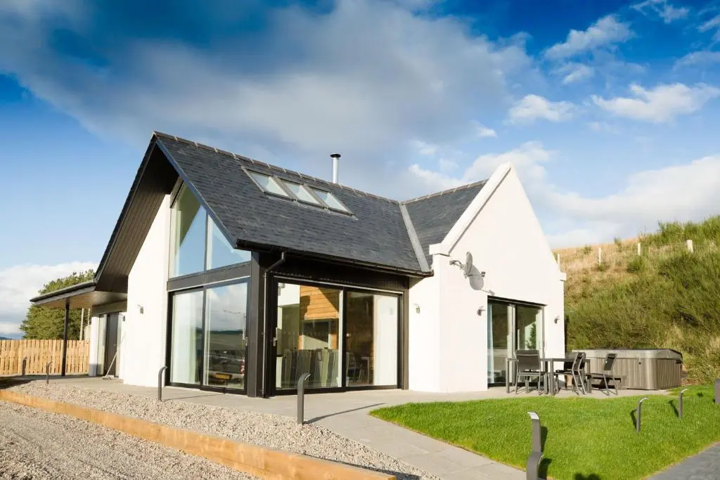 a white house with a black roof and windows at Tomdhu Lodge - Seasgair Lodges in Boat of Garten