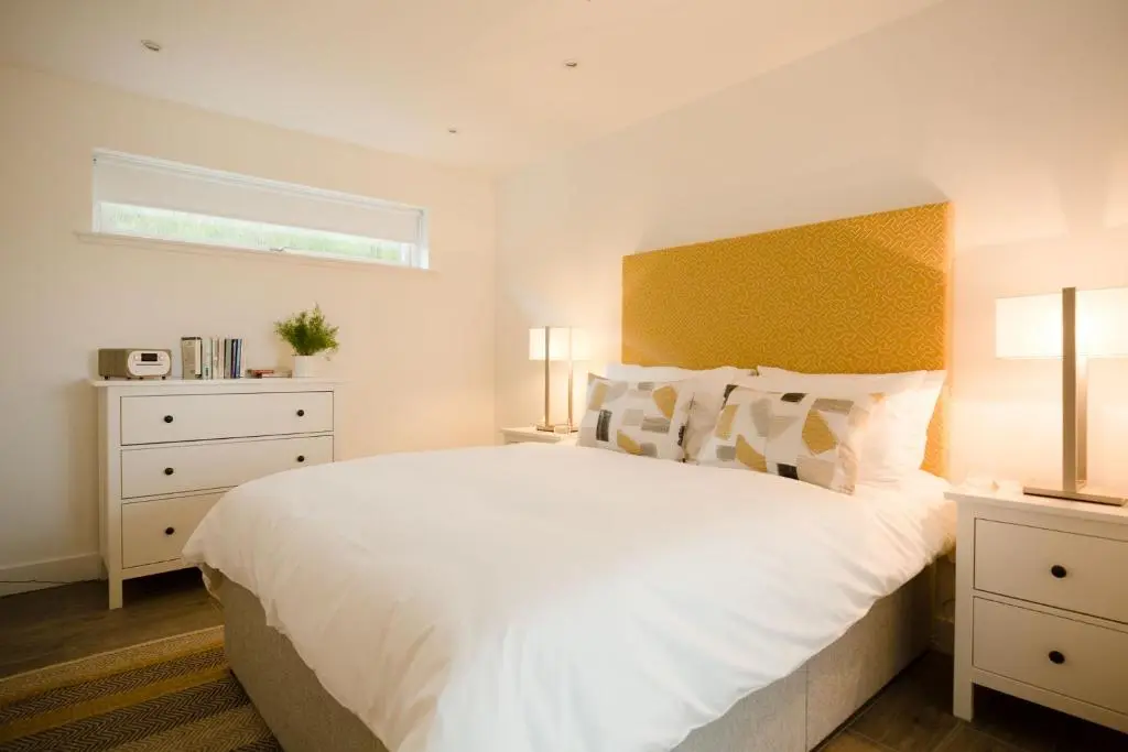 a bedroom with a large white bed and a window at Tomdhu Lodge - Seasgair Lodges in Boat of Garten