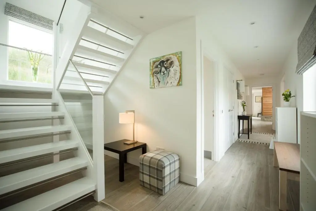 a white staircase in a living room with a table at Tomdhu Lodge - Seasgair Lodges in Boat of Garten