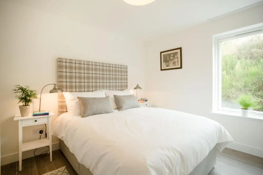 a white bedroom with a white bed and a window at Tomdhu Lodge - Seasgair Lodges in Boat of Garten