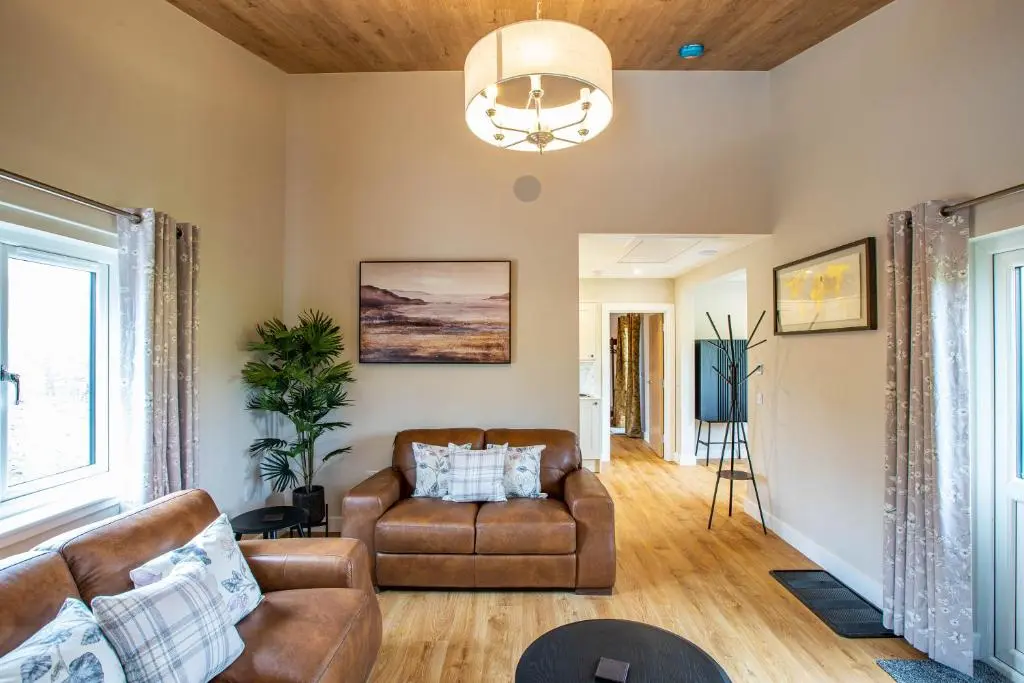 a living room with a couch and a table at Breckland Lodge 4 with Hot Tub in Belladrum
