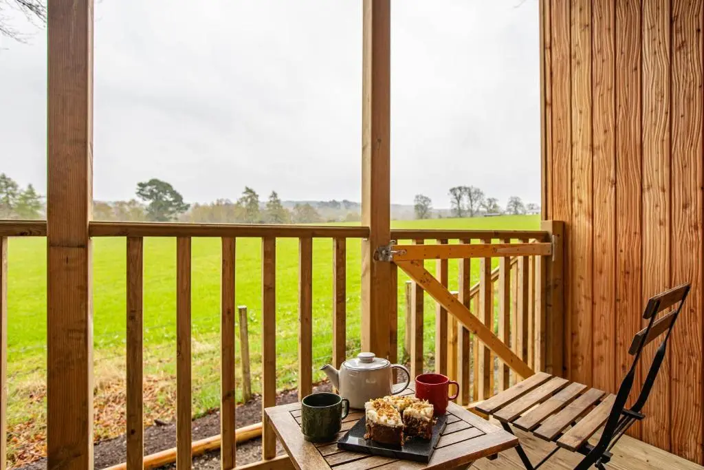 a table with a plate of food on a porch at Breckland Lodge 4 with Hot Tub in Belladrum
