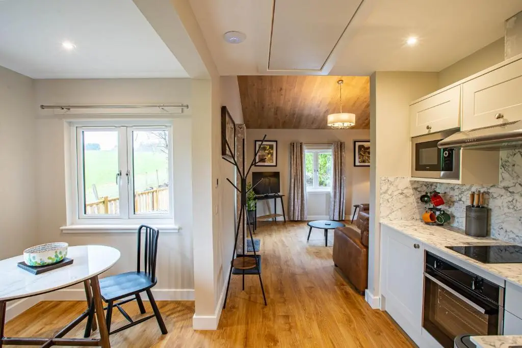 a kitchen and dining room with a table and chairs at Breckland Lodge 4 with Hot Tub in Belladrum
