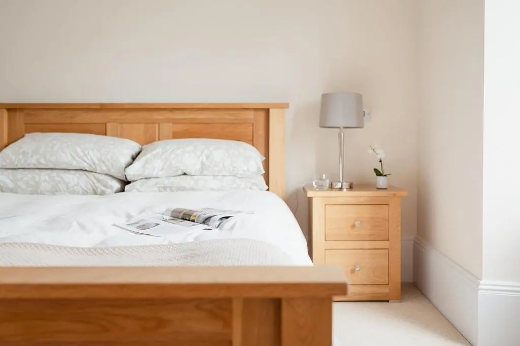 a bedroom with a wooden bed and a night stand at Craigard Lodge - Seasgair Lodges in Boat of Garten