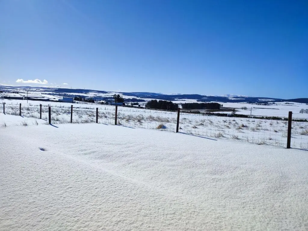 a snow covered field with a fence in the distance at Meikle Balloch in Keith