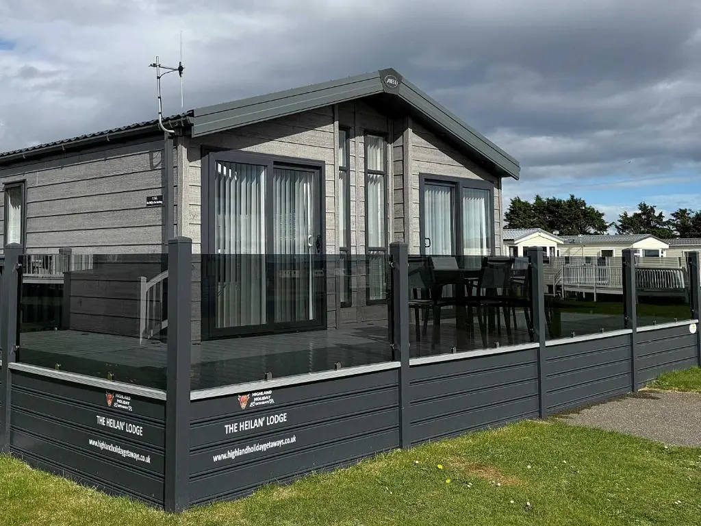 a house with a screened in porch on the grass at Highland Holiday Getaways - The Heilan' Lodge in Embo