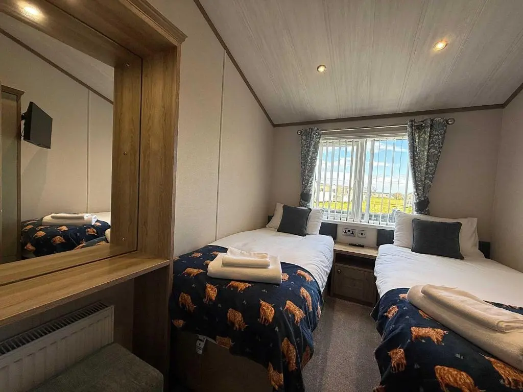 a small room with two beds and a mirror at Highland Holiday Getaways - The Heilan' Lodge in Embo