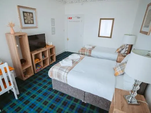 a hotel room with two beds and a television at Nairn View Guest House in Nairn