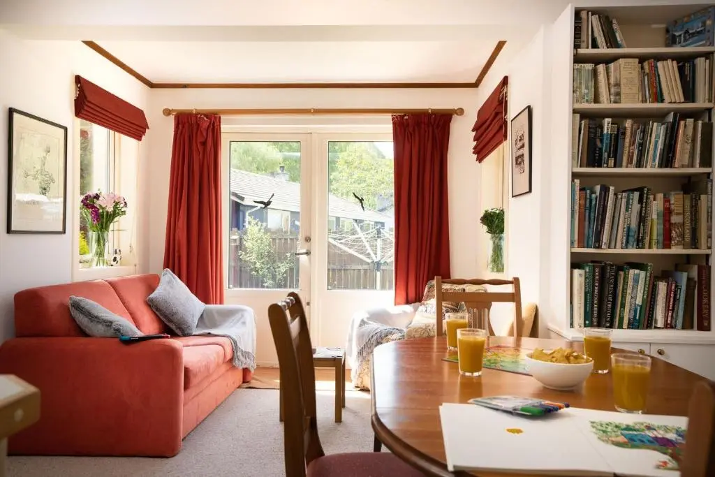 a living room with a table and a red couch at Langrick in Nethy Bridge