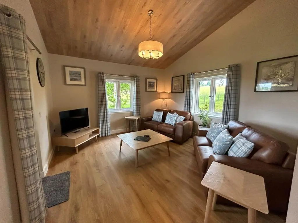 a living room with a couch and a tv at Breckland Lodge 3 with Hot Tub in Belladrum